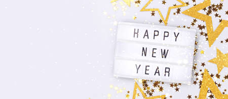 Happy New Year. Banner with lightbox and golden glittering stars confetti on a blue background with...