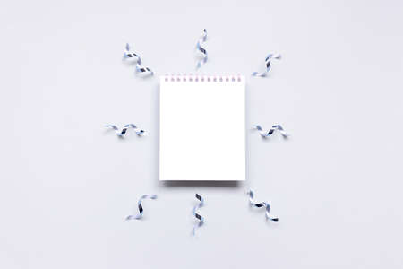 Empty notepad mockup with ribbons confetti on a blue pastel background.