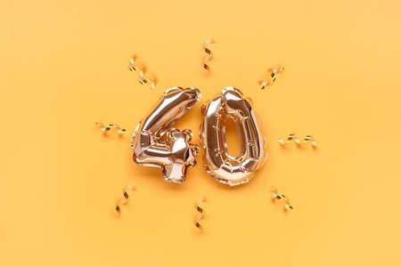Number 40 air balloons with ribbon confetti on a gold colored background.の写真素材