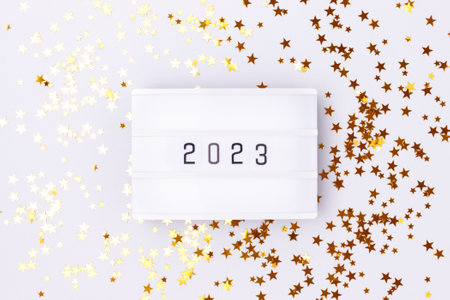 Lightbox with 2023 numbers on a blue pastel background with golden stars confetti.の写真素材