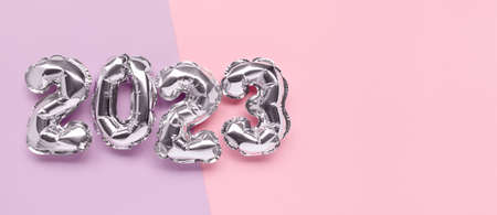 Banner with 2023 silver balloons on a pink and purple background with copy space. New Years minimal...