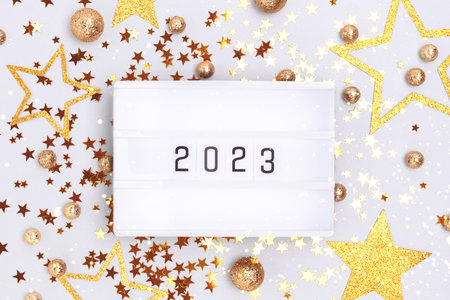 New 2023 year concept. Lightbox and golden glittering confetti on a blue background.の写真素材