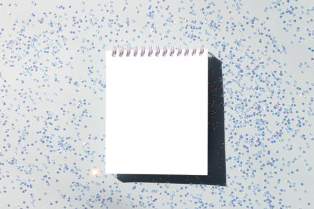 Clean notepad mockup and silver crystal confetti on a blue pastel background. Festive concept.の写真素材