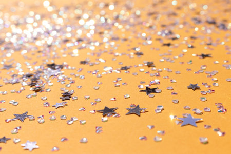 Tiny silver stars and crystals confetti scattered on a yellow background. selective focus. Shiny texture.の写真素材