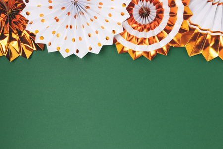 Row of golden paper fans on a green background. Festive composition with place for text.