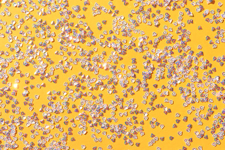 Tiny silver crystal confetti on a yellow background. Glowing festive texture.