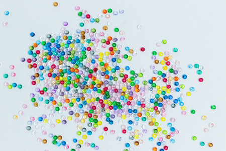 Colorful beads scattered on a blue background. Equipment for handmade accessories.