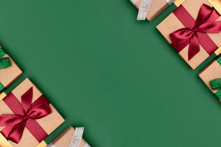 Gifts tied with multicolored ribbons on a green and golden background. Festive creative layout with copy space.の写真素材