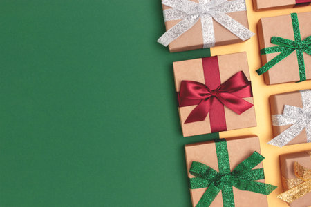 Gifts tied with multicolored ribbons on a green and golden background. Festive creative layout with...
