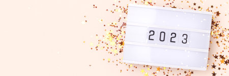 Lightbox with 2024 numbers and gold colored stars confetti on a beige background. New Year concept...