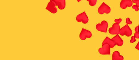 Banner with red textile hearts confetti scattered on a yellow background. Concept with copy space.の写真素材