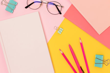 School supplies and eyeglasses on a pink and yellow background.の写真素材