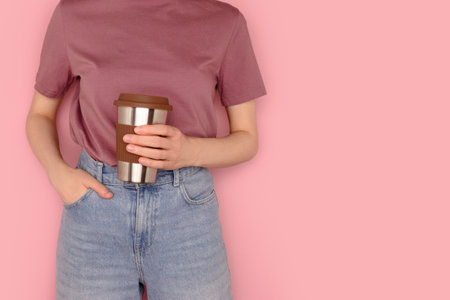 Woman hold in hands reusable coffee cup in front of pink background. Take away drinks concept with place for text.の写真素材