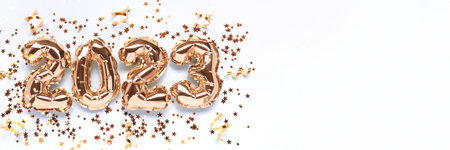 Banner with 2023 gold foil balloons, stars confetti and ribbons on a blue background. Holidays...