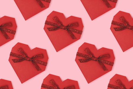 Repetitive pattern made of red gift box in a heart shape with tied glittering ribbon. Festive...