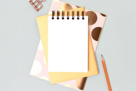 Workspace with empty notepad mock up and gold colored stationery on a blue background. Composition...