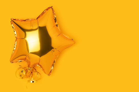 One golden air balloon in a star shape on a yellow background.の写真素材