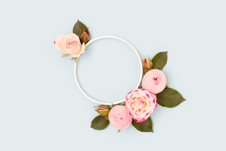Wreath made of green leaves and pink rose flowers on a blue background. Place for your design.の写真素材