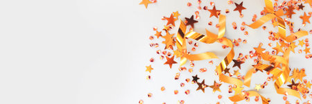 Banner with golden ribbons, stars and crystals confetti on a blue background. Selective focus.