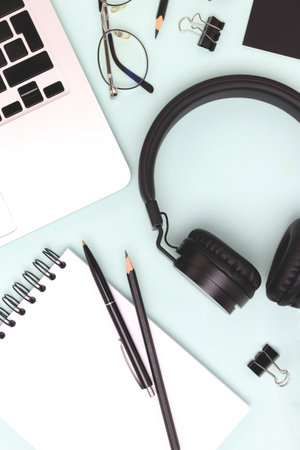 Layout with laptop, headphones and black colored stationery on a blue background. Online studying concept.の写真素材
