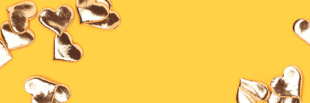 Banner with golden hearts confetti scattered on a yellow background.の写真素材