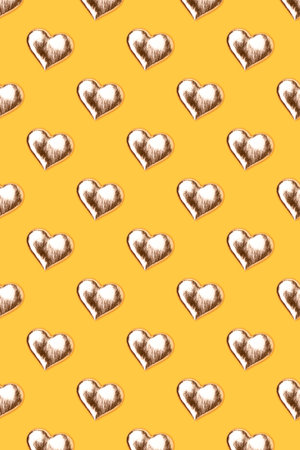 Pattern made of golden hearts on a yellow background.