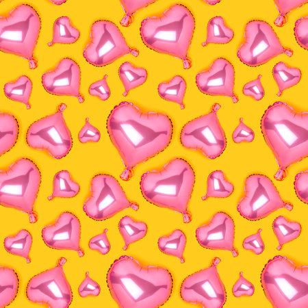 Seamless pattern made of pink inflatable balloons in a heart shape on a yellow background.の写真素材