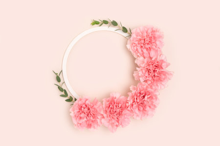 Wreath made of pink carnation flowers and green eucalyptus branches on a beige background. floral layout.の写真素材