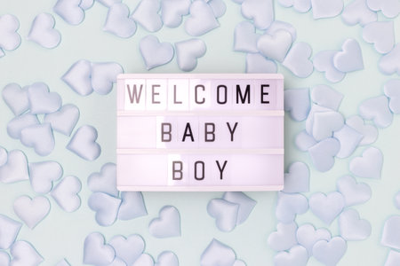 welcome baby boy. Lightbox with letters and confetti in a heart shape on a blue background. Monochrome concept.の写真素材