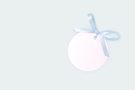 Silver round empty tag with tied blue ribbon bow. monochrome composition.の写真素材