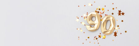 Banner with golden number 90 and shimmer stars confetti on a blue background. Festive composition with copy space.の写真素材