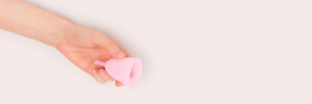 Banner with hand hold pink menstrual cup on a gray background. Zero waste concept with place for text.の写真素材