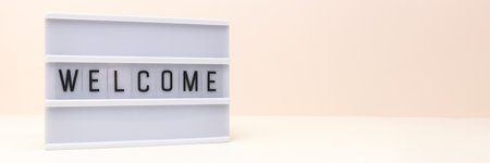 Banner with word welcome. Lightbox with letters in front of beige background. Concept with place for textの写真素材