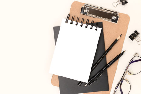 Workspace with empty notepad mockup, eyeglasses and stationery on a beige background. Back to school concept.の写真素材