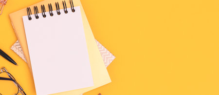 Banner with clean notepad mock up and golden stationery on a yellow background.の写真素材
