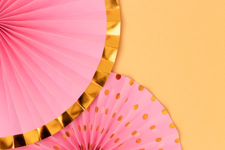 Pink paper fans on a gold glittering background. Creative concept with place for text.の写真素材