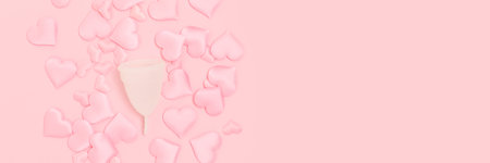 Banner with menstual cup and hearts confetti on a pink background. Zero waste period concept with copy space.の写真素材