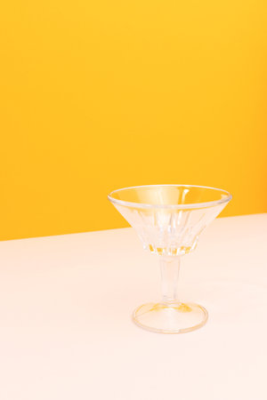 Small crystal glass in front of yellow background. Place for your design.の写真素材