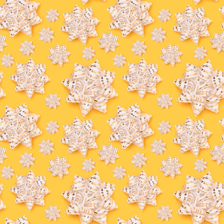 Seamless pattern made of golden ribbon bows on a yellow background.の写真素材