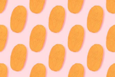 Pattern made of skein of yellow wool thread on a pink pastel background. creative concept.