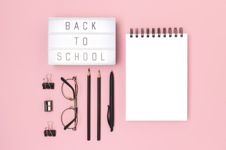 Back to school. Lightbox with letters and black colored stationery on a pink background. Empty notepad mockup.の写真素材