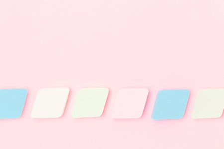 Multicolored makeup sponges neatly laid out on a pink background. Place for your design.の写真素材