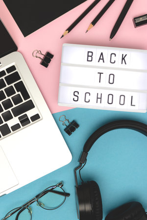 back to school. Layout with lightbox, headphones, laptop and stationery on a pink and blue background. Online education concept.の写真素材