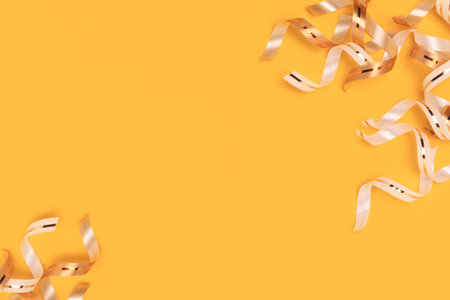 Frame made of gold colored ribbons on a yellow background. selective focus.の写真素材