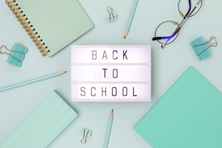 Back to school. Lightbox with letters and frame made of stationery on a blue background.