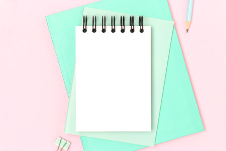 Workspace with empty notepad mock up and mint colored stationery on a pink background. Place for text.の写真素材