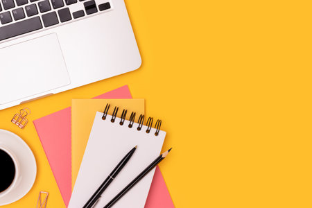Workspace with laptop, cup of coffee and office supplies on a yellow background. Business concept with place for text.の写真素材