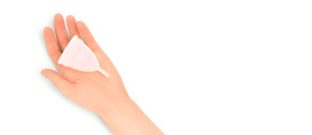 Banner with female hand hold menstrual cup on a blue pastel background. selective focus.の写真素材