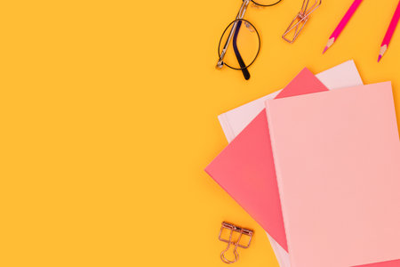 Pink colored school supplies on a yellow background. Education concept with copy space.