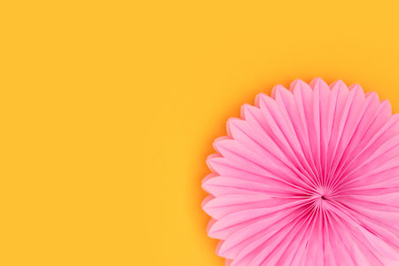 Pink tissue paper fans on a yellow background. Festive decor.の写真素材